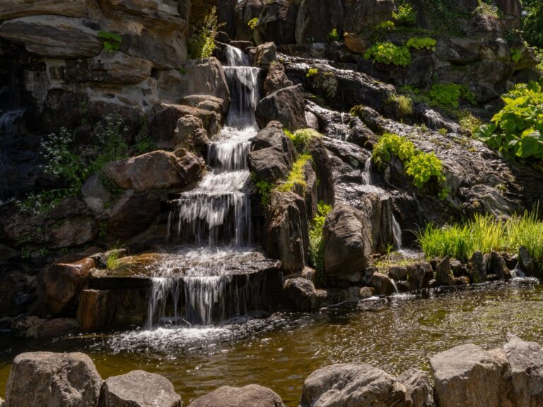 A serene waterfall flowing over rocks surrounded by greenery in Yonkers, New York.